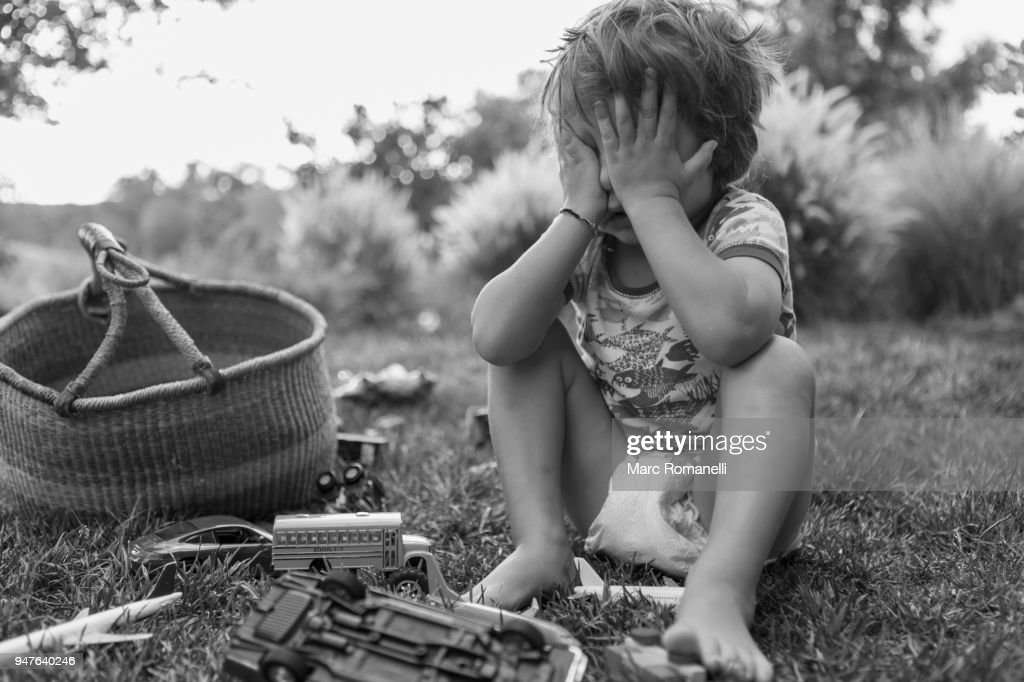 Depressed 3 Year Old Boy Playing On Green Lawn With Basket Of Toys High ...